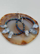 Load image into Gallery viewer, These ultra-trendy crystal nugget and glass beaded hoop earrings are perfect for any hippie or bohemian look. The dark blue glass beads give off an iridescent shimmer and blend brilliantly with the luster blue crystals, creating an eye catching contrast and a unique touch of nature-inspired beauty. Measurements: 2 1/4&quot; length
