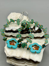 Load image into Gallery viewer, This pair of earrings features a turquoise magnesite floral bead with a vibrant orange glass bead and natural green aventurine stone chips juxtaposed against gold and blue glass beads. Measurements: 2" length 
