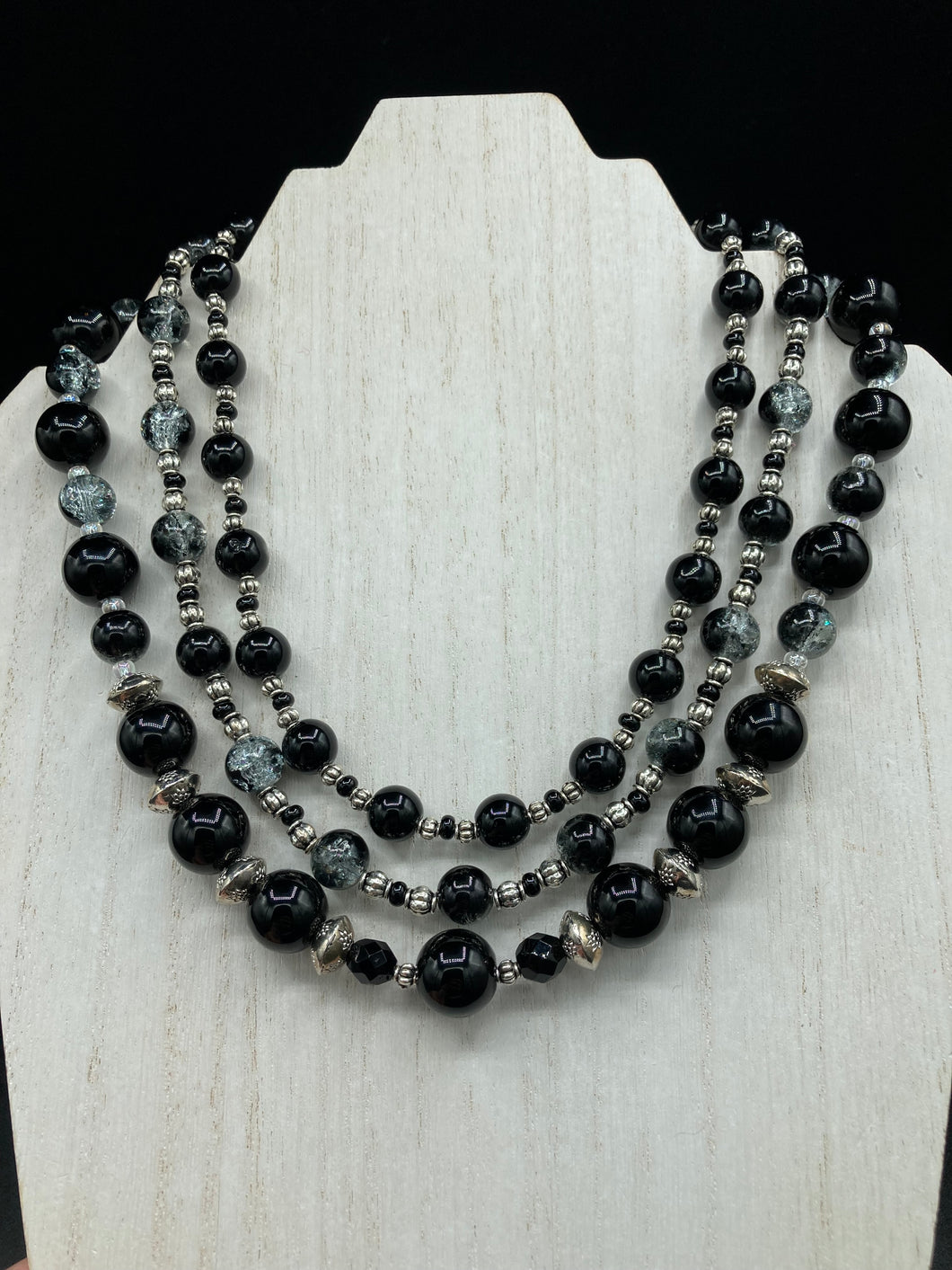 This stunning Shimmery black glass and floral metal beaded necklace features three long strands which gracefully drape around the neck. Its bold elegance is the perfect accessory for a cocktail chic outfit, a wedding, or a more minimalist look.  Measurements:    Necklace is 16 1/4” in length - adjustable to 18
