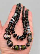 Load image into Gallery viewer, Add flair to your look with this unique large and chunky hand beaded necklace. Featuring a wide variety of mixed black glass beads in different sizes and shapes, this intricately-crafted statement piece offers a bold, hippie-chic, shabby-chic, and bohemian style.  Measurements:  Necklace is 18” in length, can be adjusted up to 20&quot;
