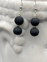 Load image into Gallery viewer, These flat matte black glass bead earrings are perfect for creating a cocktail chic ensemble. With a round shape and silver plated floral bead, this timeless piece is ideal for special occasions such as weddings. Its minimalist look exudes effortless elegance. Measurements: 1 1/4” in length
