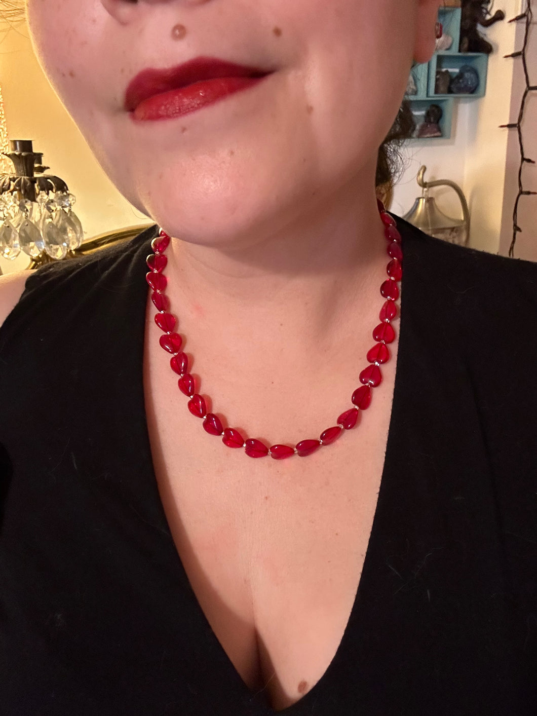 This ruby red heart-shaped glass beaded necklace features a shimmery, translucent finish and a lobster claw clasp.  Measurements:    Necklace is 18 1/2