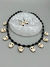 Load image into Gallery viewer, This black and white Goth-style necklace displays a series of shimmering dark-toned glass beads that gracefully encircle the neck and feature hanging skull-shaped beads. A powerful, bewitching and audacious piece of jewelry.  Measurements: 19 1/4&quot;
