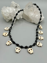 Load image into Gallery viewer, This black and white Goth-style necklace displays a series of shimmering dark-toned glass beads that gracefully encircle the neck and feature hanging skull-shaped beads. A powerful, bewitching and audacious piece of jewelry.  Measurements: 19 1/4&quot;
