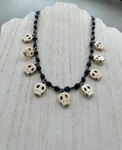 Load image into Gallery viewer, This black and white Goth-style necklace displays a series of shimmering dark-toned glass beads that gracefully encircle the neck and feature hanging skull-shaped beads. A powerful, bewitching and audacious piece of jewelry.  Measurements: 19 1/4&quot;
