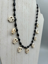 Load image into Gallery viewer, This black and white Goth-style necklace displays a series of shimmering dark-toned glass beads that gracefully encircle the neck and feature hanging skull-shaped beads. A powerful, bewitching and audacious piece of jewelry.  Measurements: 19 1/4&quot;
