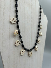 Load image into Gallery viewer, This black and white Goth-style necklace displays a series of shimmering dark-toned glass beads that gracefully encircle the neck and feature hanging skull-shaped beads. A powerful, bewitching and audacious piece of jewelry.  Measurements: 19 1/4&quot;
