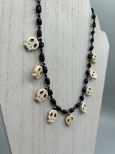 Load image into Gallery viewer, This black and white Goth-style necklace displays a series of shimmering dark-toned glass beads that gracefully encircle the neck and feature hanging skull-shaped beads. A powerful, bewitching and audacious piece of jewelry.  Measurements: 19 1/4&quot;
