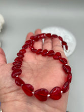 Load image into Gallery viewer, This ruby red heart-shaped glass beaded necklace features a shimmery, translucent finish and a lobster claw clasp.  Measurements:    Necklace is 18 1/2&quot; in length
