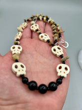 Load image into Gallery viewer, This skully necklace is full of neutral tones and is adorned with natural black obsidian and bamboo chips, as well as small glass beads. It has a unique design that creates a striking silhouette across the wearer&#39;s neck. An ideal statement piece for bold fashion enthusiasts.   Measurements:  Necklace - 19 1/4&quot;
