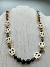 Load image into Gallery viewer, This skully necklace is full of neutral tones and is adorned with natural black obsidian and bamboo chips, as well as small glass beads. It has a unique design that creates a striking silhouette across the wearer&#39;s neck. An ideal statement piece for bold fashion enthusiasts.   Measurements:  Necklace - 19 1/4&quot;
