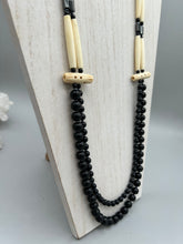 Load image into Gallery viewer, This two-strand necklace features a selection of natural black obsidian stone, hematite, bone, and glass beads. This neutral-hued accessory enhances any ensemble.  Measurements:   Necklace is 29” in length, can be adjusted up to 30&quot; in length  
