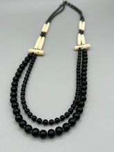 Load image into Gallery viewer, This two-strand necklace features a selection of natural black obsidian stone, hematite, bone, and glass beads. This neutral-hued accessory enhances any ensemble.  Measurements:   Necklace is 29” in length, can be adjusted up to 30&quot; in length  
