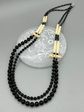 Load image into Gallery viewer, This two-strand necklace features a selection of natural black obsidian stone, hematite, bone, and glass beads. This neutral-hued accessory enhances any ensemble.  Measurements:   Necklace is 29” in length, can be adjusted up to 30&quot; in length  
