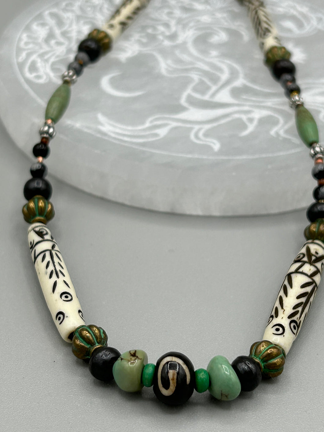 This exquisite necklace features natural ruby zoisite, snowflake obsidian, turquoise magnesite, bone, glass and metal beads, offering a variety of sizes, shapes, textures, and colors.