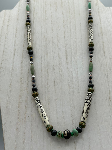 This exquisite necklace features natural ruby zoisite, snowflake obsidian, turquoise magnesite, bone, glass and metal beads, offering a variety of sizes, shapes, textures, and colors.