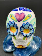 Load image into Gallery viewer, Inspired by nature, this ceramic skull statuette is full of vibrant color and intricate details that I hand painted. The primary color is white with multi-color floral motifs that are painted across the skull, along with hearts and leaves and lively colorful accents around the entire skull. 
