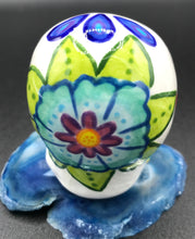 Load image into Gallery viewer, Inspired by nature, this ceramic skull statuette is full of vibrant color and intricate details that I hand painted. The primary color is white with multi-color floral motifs that are painted across the skull, along with hearts and leaves and lively colorful accents around the entire skull. 

