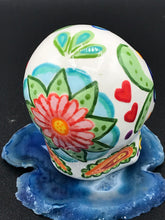 Load image into Gallery viewer, Inspired by nature, this ceramic skull statuette is full of vibrant color and intricate details. The primary color is white with multi-color floral motifs that are painted across the 
