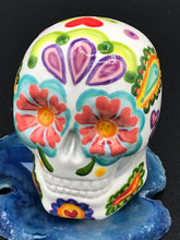 Load image into Gallery viewer, Inspired by nature, this ceramic skull statuette is full of vibrant color and intricate details that I hand painted. The primary color is white with multi-color floral motifs that are painted across the skull, along with hearts and leaves and lively colorful accents around the entire skull. 
