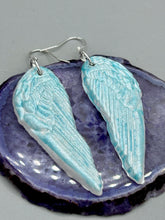 Load image into Gallery viewer, Light baby blue wings earrings made of polymer clay.  These earrings are designed to face forward when worn instead of the front wings showing on the side.

