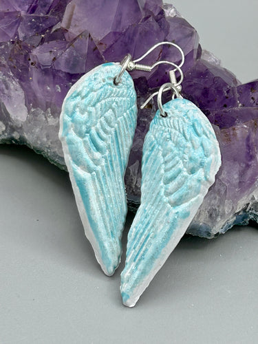 Light baby blue wings earrings made of polymer clay.  These earrings are designed to face forward when worn instead of the front wings showing on the side.