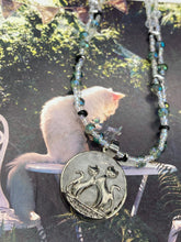 Load image into Gallery viewer, This stylish necklace features a shimmery sterling silver quartz pendant with cats and stars, making it the perfect accessory for any cat lover. With two-hole silver and black beads that stand out against the light aquamarine glass beads, this double strand necklace holds a round kitty pendant made with various hues of clear and iridescent glass beads. Add a touch of purrfection to your look with this statement piece.  Measurements:  Necklace is 15”adjustable up to 18&quot; 
