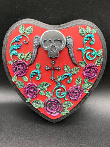 This Memento Mori Wall Art Decor is a one-of-a-kind art piece, skillfully crafted with a black polymer clay skull and wings on a dark red wood frame, decoratively woven with dark red roses and vines. It's perfect for adding an eye-catching touch to any wall and makes a unique, bold gift.  Measurements: H 6 3/4