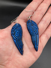 Load image into Gallery viewer, These eye-catching electric blue angel wings earrings are expertly crafted from polymer clay. Featuring an innovative design, they ensure the wings face forward when worn.
