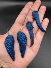 Load image into Gallery viewer, These eye-catching electric blue angel wings earrings are expertly crafted from polymer clay. Featuring an innovative design, they ensure the wings face forward when worn.
