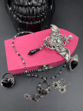 Load image into Gallery viewer, This unique handmade Pink Spooky Glam Wood Coffin Ring Box offers a statement piece for your witchy home decor. Its macabre collections boast a black and pink wood coffin with large shimmery bat embellishments and decorative black crystals around the exterior. Open up the box to find a bright turquoise mandala fabric and a tiny black crystal bat decoration for a truly eerie feel.
