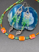 Load image into Gallery viewer, This unique, double-strand necklace consists of a blend of glass beads, including multi-green and rectangular, faceted orange glass beads, and is accented with gold and light blue elements. The vibrant combination is perfect for any summer look and will enhance any outfit.  Measurements:  Necklace is 16” and can be adjusted up to 18&quot;
