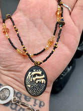 Load image into Gallery viewer, This spooky resin anatomical heart pendant is too cute!!! The pendant is made of resin with brass metal backing. An assortment of floral metal beads to give it a contrast to the soft, dainty style of the glass beaded necklace. Tiny shimmer black glass beads with yellow and orange glass beads to give it a pop of color.  Necklace measures 16” adjustable up to 18” in length, pendant is 1 1/4” Height
