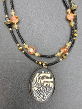 Load image into Gallery viewer, This spooky resin anatomical heart pendant is too cute!!! The pendant is made of resin with brass metal backing. An assortment of floral metal beads to give it a contrast to the soft, dainty style of the glass beaded necklace. Tiny shimmer black glass beads with yellow and orange glass beads to give it a pop of color.  Necklace measures 16” adjustable up to 18” in length, pendant is 1 1/4” Height

