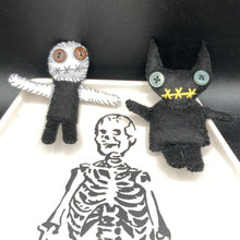 Load image into Gallery viewer,  Skinny black and white Voodoo Doll stands at 3 7/8&quot; in height. Black torso and legs with white arm and head.  Stylish brown buttons for eyes, but his lips are sowed shut of course.  Black Devil Voodoo Doll has yellow mouth and cute little black horns of course, white buttons for eyes: 3 3/8&quot; in height.
