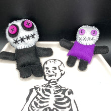 Load image into Gallery viewer, Creepy black and purple  Voodoo Doll stands tall at 3 3/8&quot; in height.  He’s all black like a shadow but has a round white head.  Bright purple buttons for eyes are perfect to see you better with.  Mini socially awkward black and purple Voodoo Doll stands at 2 3/4&quot; in height.  He has a bright purple torso with black limbs and a large white head and matching purple biddy eyes.  
