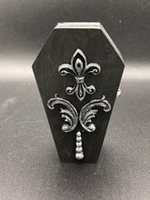 Load image into Gallery viewer, This vintage-inspired coffin ring box will make a spooky yet cute addition to any jewelry collection. The sleek black box has eye-catching black and gray embellishments, while the interior is beautifully decorated with a vivid turquoise blue fabric and a highly detailed black and silver cross with dark red roses. Function and style meet with this unique and stylish piece.
