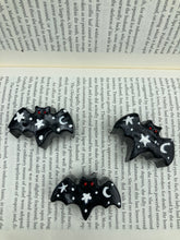 Load image into Gallery viewer, Cute and spooky magnet design to adorn your refrigerator, lockers, workstation, toolbox, or dishwasher. This hand-sculpted clay bat statuette all black with white stars to recreate a starry night sky. H 1” x W 2” x D 1/2”
