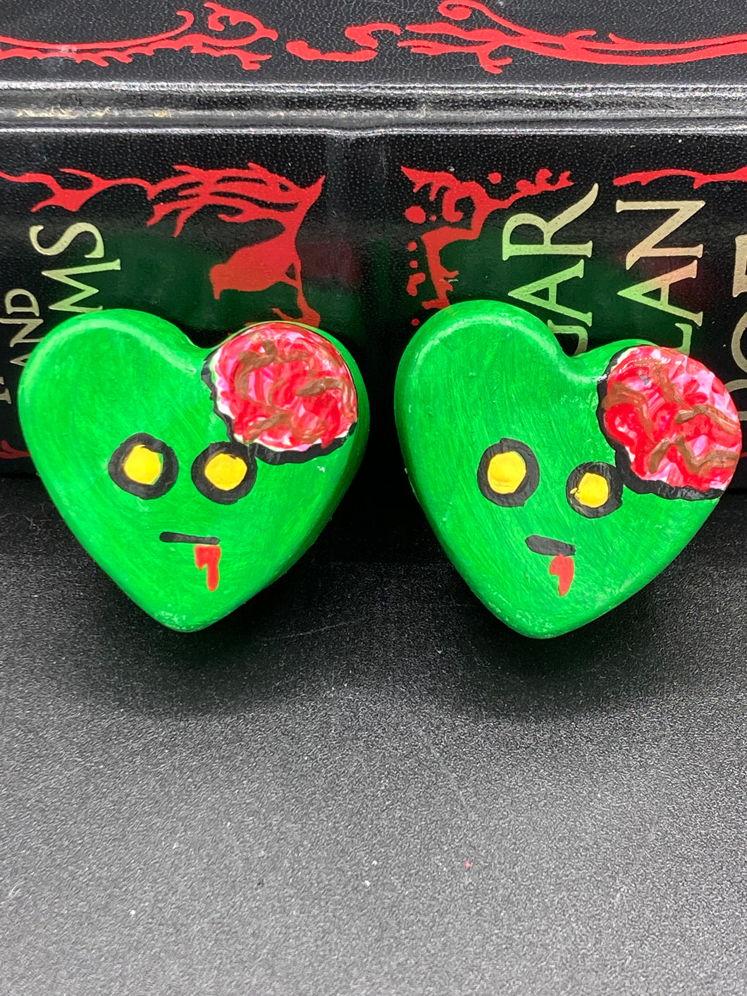 Perfect cute and spooky Halloween item to add to your fridge, locker, cubicle or toolbox. This handcrafted, bright green, heart-shaped magnet features an intricate, exposed brains-inspired zombie design.  Measurements: H 1 1/2” x W 1 5/8” x D 1/2”
