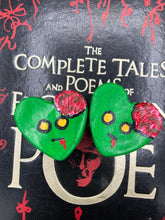 Load image into Gallery viewer, Perfect cute and spooky Halloween item to add to your fridge, locker, cubicle or toolbox. This handcrafted, bright green, heart-shaped magnet features an intricate, exposed brains-inspired zombie design.  Measurements: H 1 1/2” x W 1 5/8” x D 1/2”
