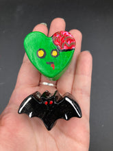 Load image into Gallery viewer, Perfect cute and spooky Halloween item to add to your fridge, locker, cubicle or toolbox. This handcrafted, bright green, heart-shaped magnet features an intricate, exposed brains-inspired zombie design. All black bat magnet with white highlights and red eyes.

