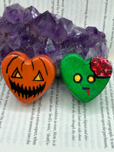 Load image into Gallery viewer, Perfect cute and spooky Halloween item to add to your fridge, locker, cubicle or toolbox.   This hand-crafted bright orange heart-shaped magnet showcases a Jack o Lantern inspired design. Cute green heart-shaped zombie with exposed brain magnet.  Measurements: H 1 1/2” x W 1 5/8” x D 1/2”
