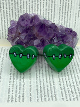 Load image into Gallery viewer, Perfect cute and spooky Halloween item to add to your fridge, locker, cubicle or toolbox. This hand-crafted light and dark green heart-shaped magnet showcases a Frankenstein-inspired design.  Measurements: H 1 1/2” x W 1 5/8” x D 1/2”
