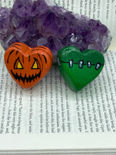 Load image into Gallery viewer, Perfect cute and spooky Halloween item to add to your fridge, locker, cubicle or toolbox. This hand-crafted light and dark green heart-shaped magnet showcases a Frankenstein-inspired design.  Bright orange heart-shaped magnet showcases a Jack O Lantern inspired design.  Measurements: H 1 1/2” x W 1 5/8” x D 1/2”
