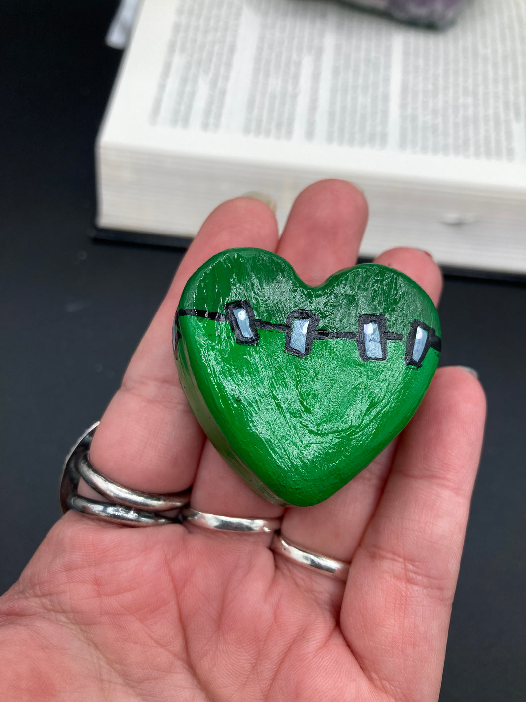Perfect cute and spooky Halloween item to add to your fridge, locker, cubicle or toolbox. This hand-crafted light and dark green heart-shaped magnet showcases a Frankenstein-inspired design.  Measurements: H 1 1/2” x W 1 5/8” x D 1/2”