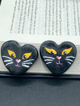 Load image into Gallery viewer, Perfect cute and spooky Halloween magnet art to add to your fridge, locker, cubicle or toolbox.  This hand-crafted heart-shaped magnet features a figurine of a black cat with distinctive yellow eyes. Measurements: H 1 1/2” x W 1 5/8” x D 1/2”
