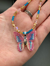 Load image into Gallery viewer, This delicate butterfly pendant is crafted from a basil leaf and adorned with accents of pink, gold and blue. A shining glass beaded necklace crafted from beads of varying shades of pink, gold, and blue, creates a beautiful accompaniment to the butterfly wings. Wear this ravishing necklace and butterfly jewelry pendant to embody the spirit of warm Spring and Summer days. 16 1/4” in length adjustable up to 18&quot;
