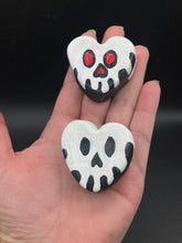 Load image into Gallery viewer, Perfect cute and spooky Halloween magnet art to add to your fridge, locker, cubicle or toolbox.  This hand-crafted black heart-shaped magnet features a white skull figurine  with distinctive red and black eyes.   Measurements: H 1 1/2” x W 1 5/8” x D 1/2”
