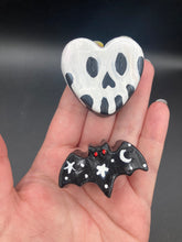 Load image into Gallery viewer, Perfect cute and spooky Halloween magnet art to add to your fridge, locker, cubicle or toolbox.  This hand-crafted black heart-shaped magnet features a white skull figurine  with distinctive black eyes. Cute all light black bat with white starts and moon and with red eyes magnet.
