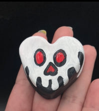 Load image into Gallery viewer, Perfect cute and spooky Halloween magnet art to add to your fridge, locker, cubicle or toolbox.  This hand-crafted black heart-shaped magnet features a white skull figurine  with distinctive red eyes.   Measurements: H 1 1/2” x W 1 5/8” x D 1/2”
